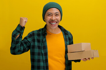 Happy Asian customer joyfully raises his arm in a YES gesture while holding package parcel...