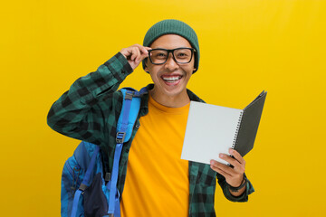 A happy young Asian student, dressed in a beanie hat and casual clothes, sporting eyeglasses and...