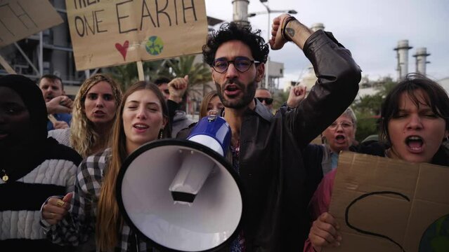 Multi-ethnic group of activists people gathered to protest climate change, displaying banners warning of global warming and calling for recycling and environmental awareness.