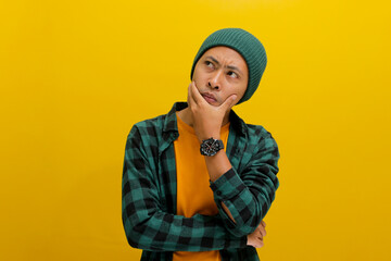 Thoughtful young Asian man, wearing a beanie hat and casual shirt, rests his hand on his chin, looking aside at empty copy space, deeply engrossed in thought and planning for the future