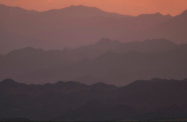 Fototapeta premium Misty steppe and desert mountains at sunset with purple and pink gradient in Asia in Southern Kazakhstan