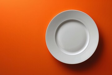 Top view of a white empty plate on a bright orange background with shadow