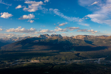 Drone view high peaks with snow under clouds sky. Forest and river below. Mountain landscape. Canada