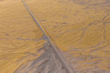Road through brown valley volcanic lava covered with ash and sand. Top drone photo. East of Iceland