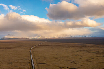Road through valley of volcanic lava, covered with ash and sand. Sunset clouds. East of Iceland.