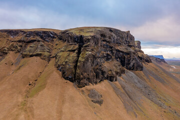 Aerial view high mountain in east of Iceland. High rocks covered with moss. Blue gray cloudy sky.