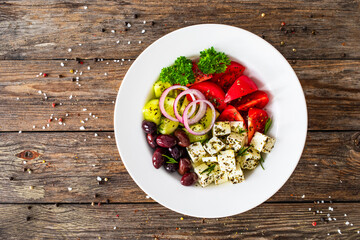 Greek style salad - fresh vegetables with feta cheese and kalamata olives served in white bowl on...