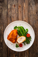 Cutlet de Volaille, wrapped chicken cutlet served with cooked green asparagus on wooden table
