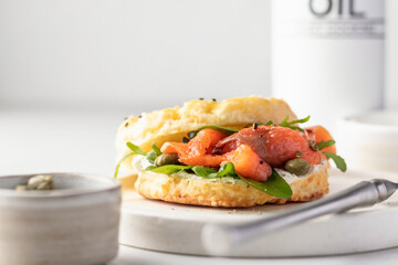 Homemade bagel sandwich with smoked salmon, cream cheese, capers and spinach for healthy breakfast on white kitchen background, text space