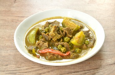 spicy boiled slice beef meat with eggplant in coconut milk green curry soup on plate
