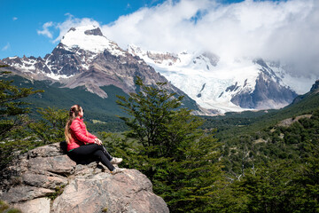 Turista sentada en una gran roca disfrutando de los paisajes de El Chalten, en la Patagonia...