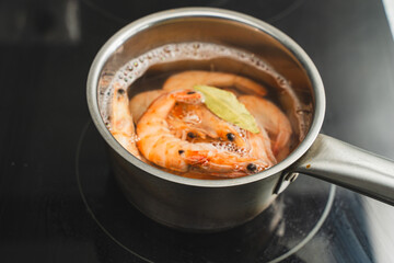 The shrimp is boiled in water in a stainless steel pot on an induction hob. Fresh red shrimps are...