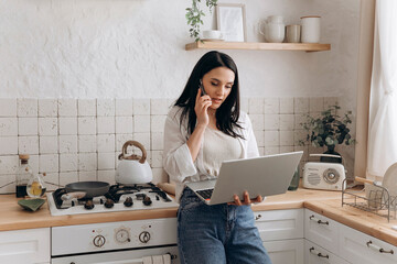 Confident young woman freelancer successfully balancing remote work and home chores, talk on the...