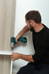 Man using cordless drill to assemble furniture in a modern home setting
