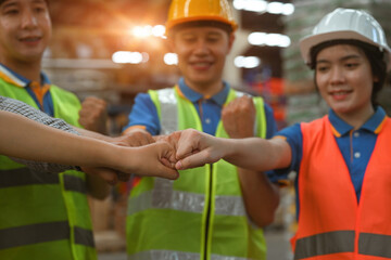 Close-up Group of industrial warehouse workers bumping fists together, successful or deal...