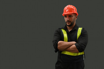 Portrait studio shot of a professional Caucasian man in an orange hard helmet and reflective safety...