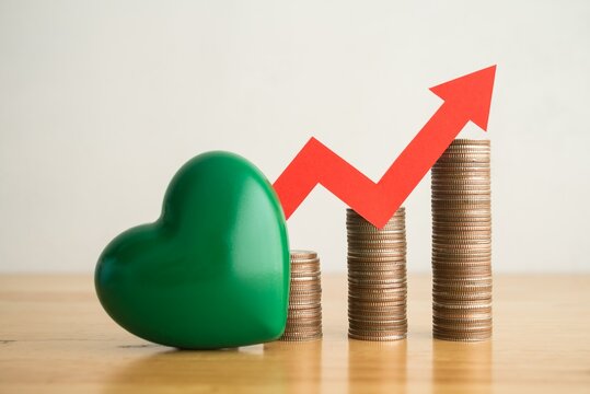 Green heart, stack coins and growth red graph with white wall background. ESG (Environmental, social, governance), green economy, sustainability social responsibility in business concept.