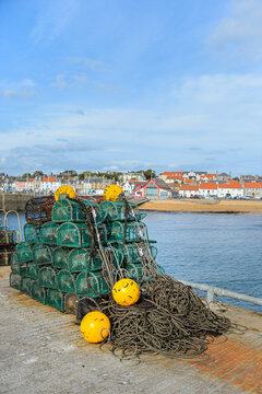 Lobster and crab baskets with yellow buoys on a jetty at Anstruther (Ainster or Enster) in Fife, on the east coast of Scotland. Vertical portrait format with copy space.
