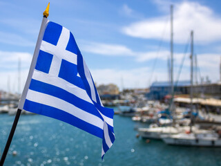 National flag of Greece fluttering in the wind at sea harbor