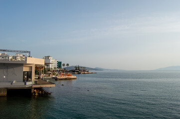 a pier on the water next to a beach with people in it