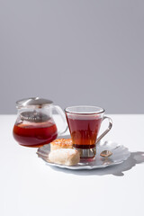 Una taza de té rojo con pasteles y dulces sobre mesa blanca y fondo gris	