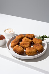 Plato de croquetas fritas con salsa de tomate y mayonesa aperitivo sobre fondo gris y blanco