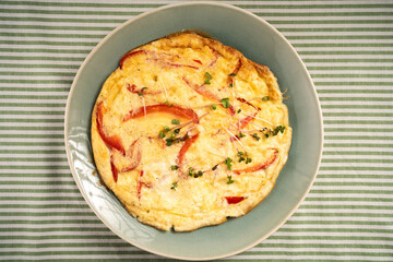 omelette with red pepper and cheese, top view on a rustic plate