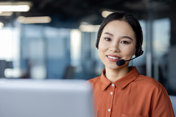 A professional woman wearing a headset, smiles warmly, displaying approachability and customer...