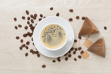 Cup of coffee made using pyramid on wooden background, top view