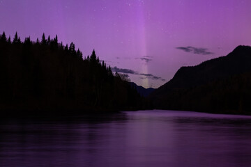 Beautiful magenta aurora borealis and pillar of light reflected in river in the Jacques-Cartier National Park, Stoneham-and-Tewksbury, Quebec, Canada