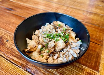close up roasted chicken charsiu bbq style in black bowl with on wooden dining table in traditional classic japan japanese rice bowl bento hawker restaurant style