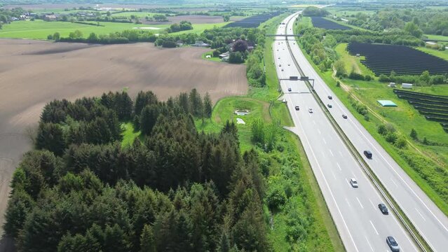 Drone view of a highway in Germany with a lot of traffic and many green fields around it.