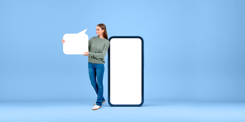 Woman holding a blank speech bubble next to a large smartphone m