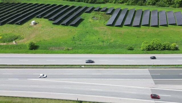 Drone flight on a German highway with lots of traffic and large solar panels next to the road.