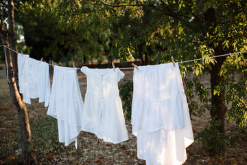 White dresses hanging on rope with pins outdoor close up.