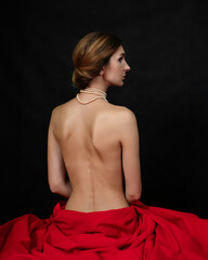 A naked girl is sitting in a red cloth in half a turn