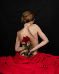 A naked girl is sitting in a red cloth holding a rose