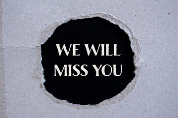 We will miss you words written on ripped paper with black background. Conceptual we will miss you...