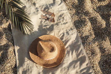 Straw hat, sunglasses, towel, on beach sand background. Aesthetic lifestyle, summer vacation...