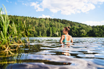 Swimming in lake in Finland. Woman in summer at beach. Finnish bathing in water in nature. Back...