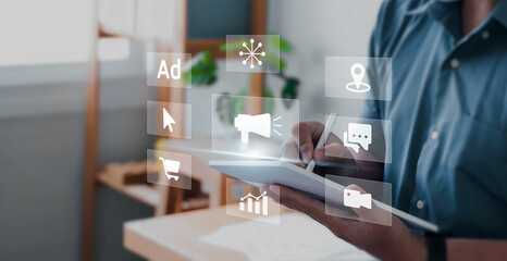 Digital marketing concept with businessman using tablets creating online adverts to increase sales. Using social media and websites for traffic and awareness, working in an office.