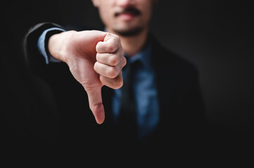 Close up of Young businessman showing thumbs down sign, dislike result or angry attitude, looks with negative expression and disapproval. Disagreement rejection, disgust and negative expressions.