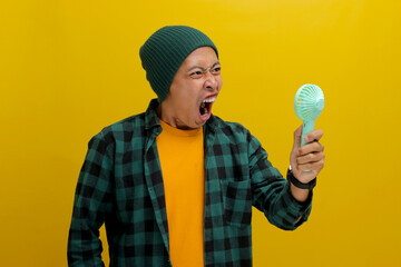 Angry Asian man, wearing a beanie hat and casual shirt, shouts and yells while holding a handheld...