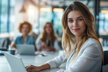 portrait of a young business woman working on her laptop in an office with a team in the background