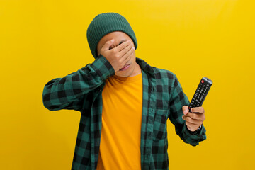 Anxious young Asian man, dressed in a beanie hat and casual shirt, appears stressed while holding a...