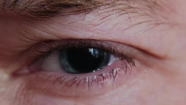 Macro shot of junkie man's eye with dilated pupil. Eye drops after a visit to an ophthalmologist. Drug influence concept.