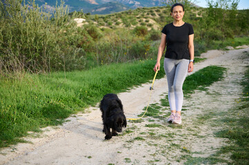 Full size shot of beautiful happy smiling woman walking her dog in mountains nature outdoors.
