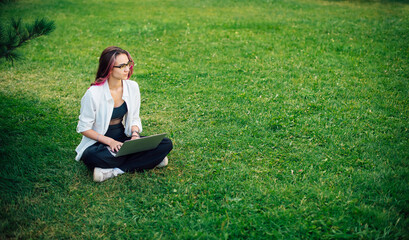 Focused young businesswoman freelancer typing on her laptop working outdoors.