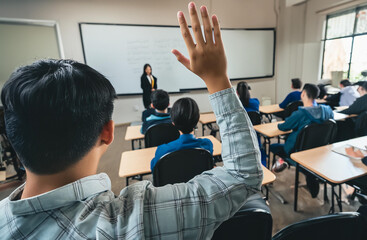 Student raises hand in classroom. View from behind.