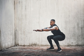 Man, fitness and squatting with earphones in city for strong muscle, balance or exercise for...